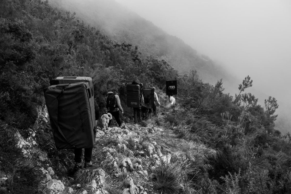 La aproximación: colchonetas a la espalda por un sendero entre la niebla.